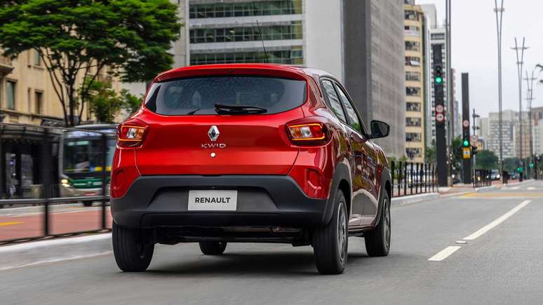 A red Renault Kwid car driving on a city street, captured from the rear side.