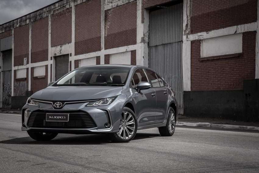 A silver Toyota sedan parked on a street in front of an industrial-style building with brick walls and metal shutters.