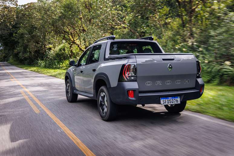 A gray Renault Oroch pickup truck driving down a rural road surrounded by greenery.