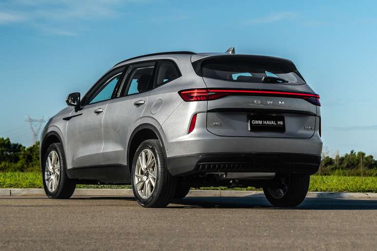 Rear view of a silver GWM Haval H6 SUV parked on a road with greenery in the background.