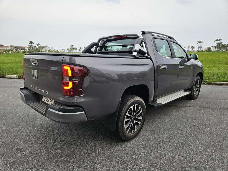 A gray pickup truck parked on a road, showcasing the rear and side view, with a grassy area in the background.