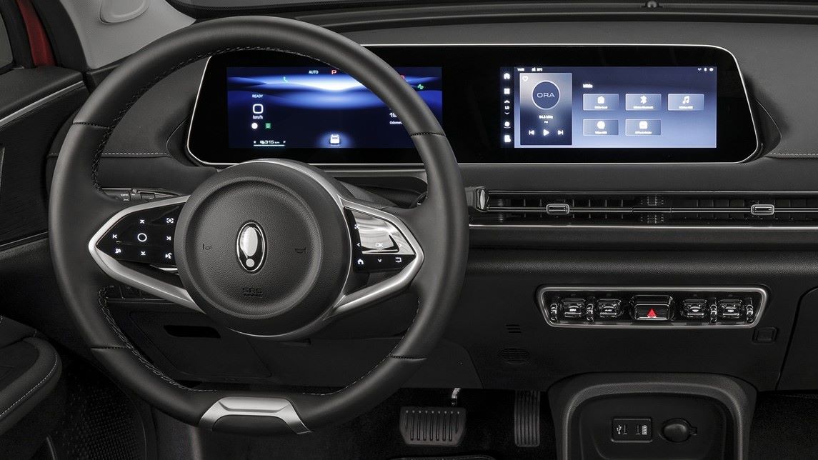 Interior de um carro com volante moderno e painel digital, exibindo múltiplas funções e controles.