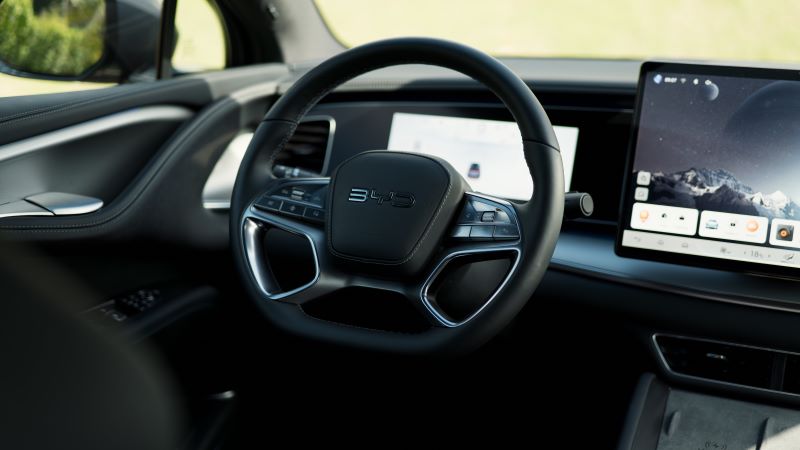 Interior view of a car dashboard featuring a modern steering wheel and a touchscreen display.
