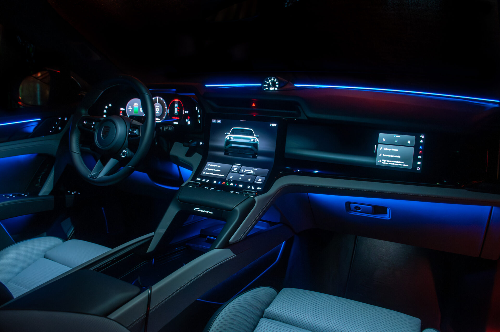 Interior de um carro esportivo com iluminação ambiente em azul, painel digital e volante.