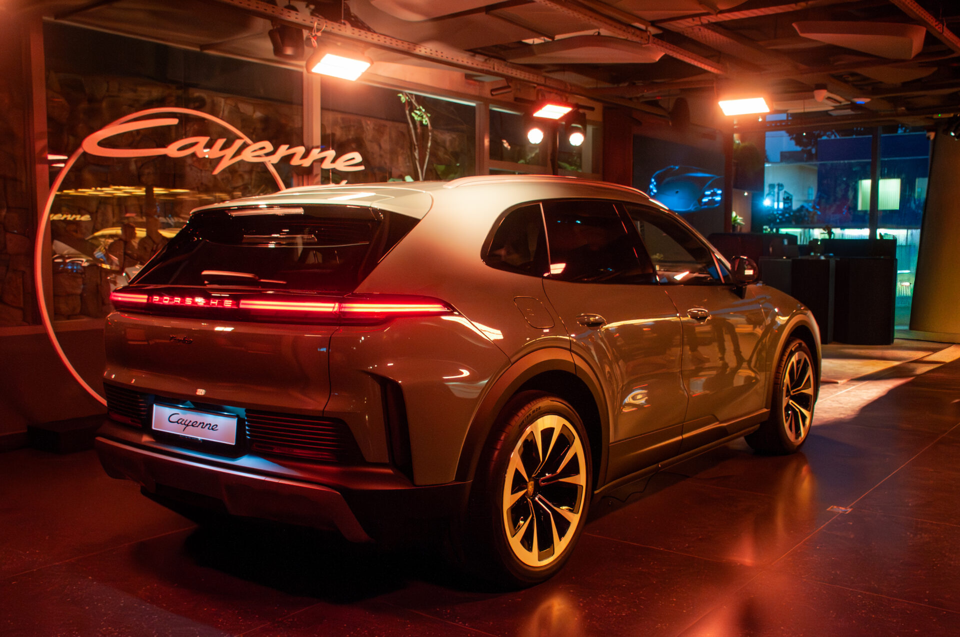 Vista traseira do Porsche Cayenne em um ambiente iluminado, destacando suas linhas elegantes e detalhes modernos.