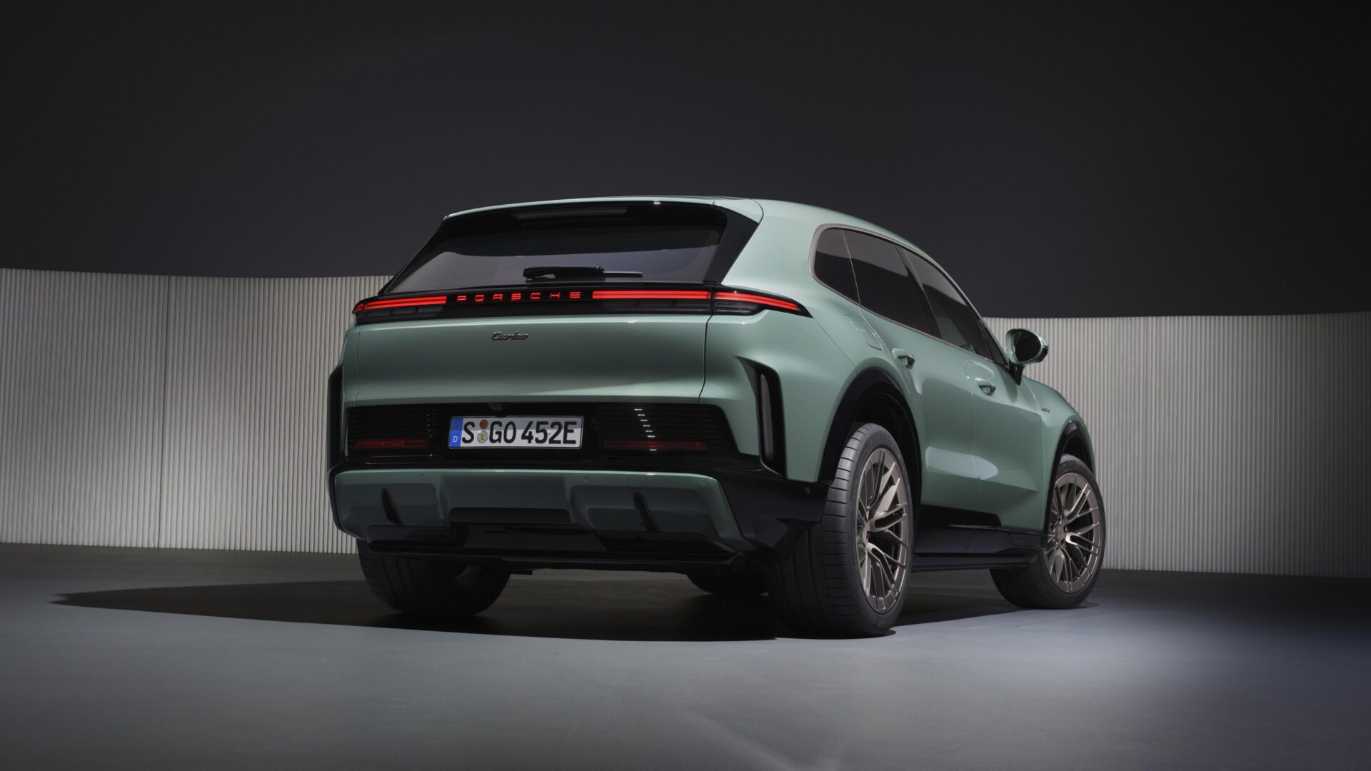 Imagem do traseira de um SUV Porsche de cor verde, com destaque para as lanternas traseiras e rodas modernas.
