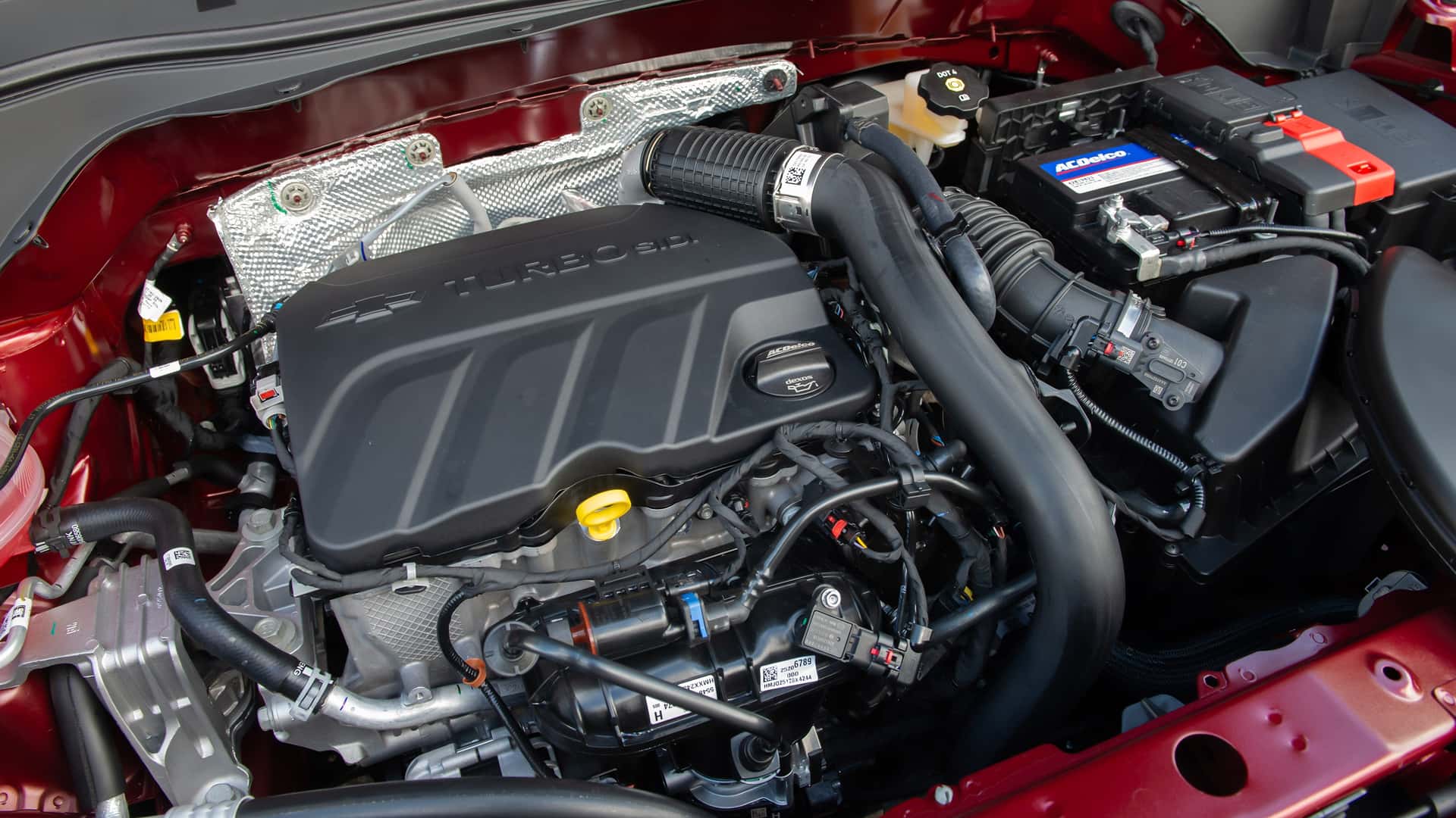 Motor turbo em compartimento de veículo, destacando componentes como bateria e mangueiras.