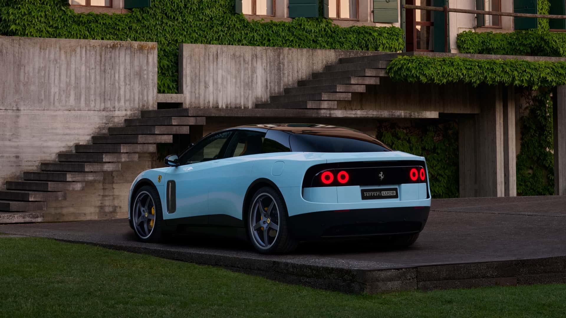 Um carro esportivo da Ferrari em uma área externa, com uma estrutura de concreto ao fundo e escadas. O veículo tem uma pintura azul clara e detalhes em preto, destacando-se no ambiente natural.