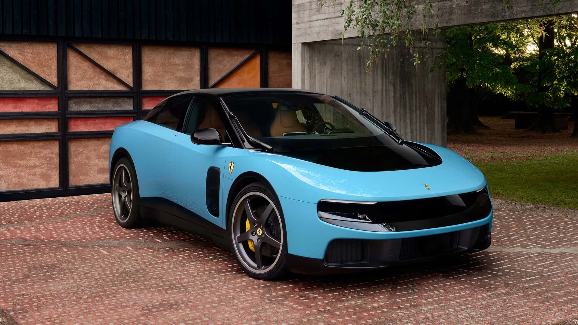 Carro esportivo da Ferrari na cor azul claro com detalhes em preto, estacionado em um ambiente moderno com paredes texturizadas e natureza ao fundo.