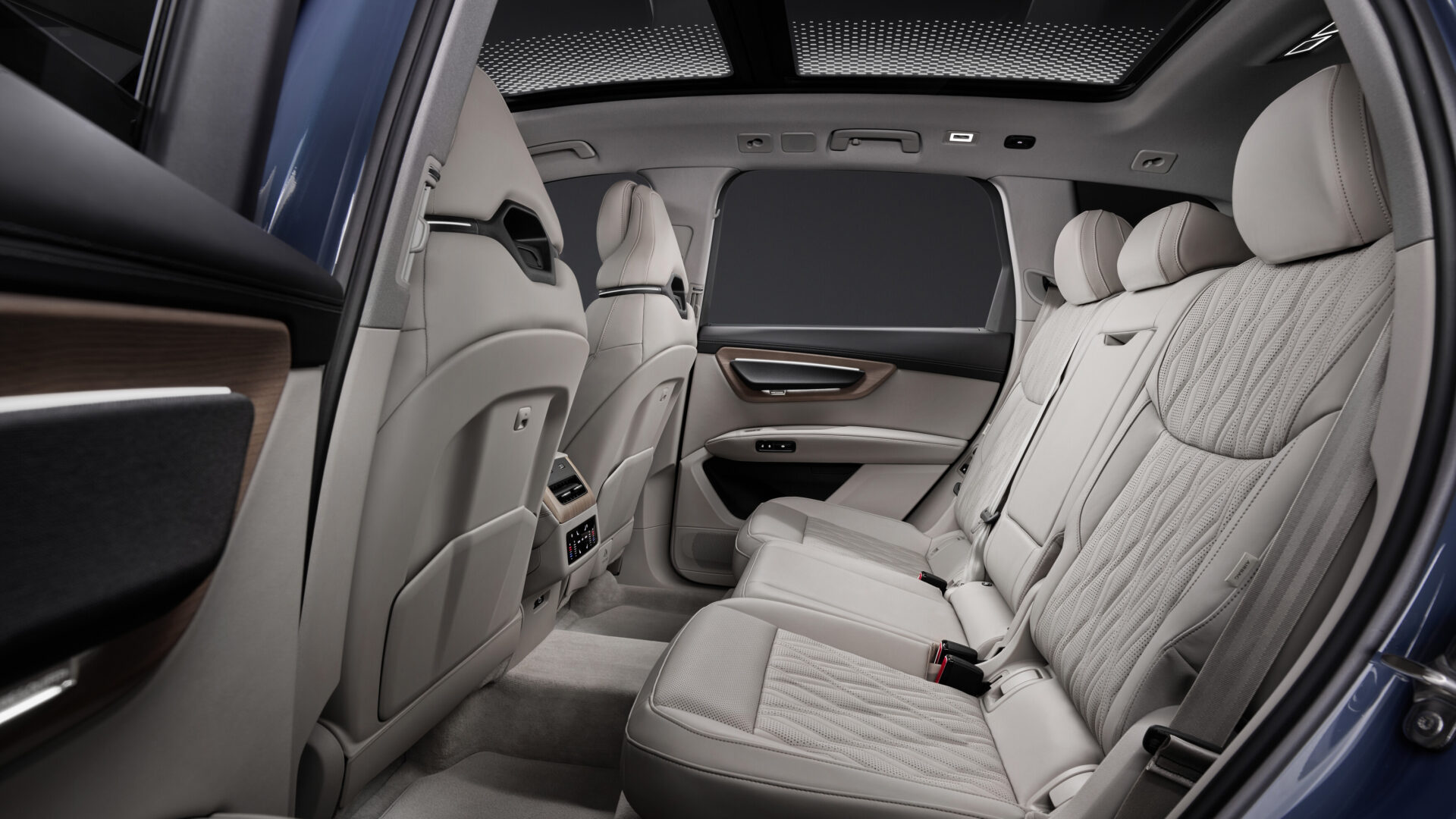 Interior view of the back seats of a luxury car, featuring comfortable leather upholstery, panoramic sunroof, and modern design elements.