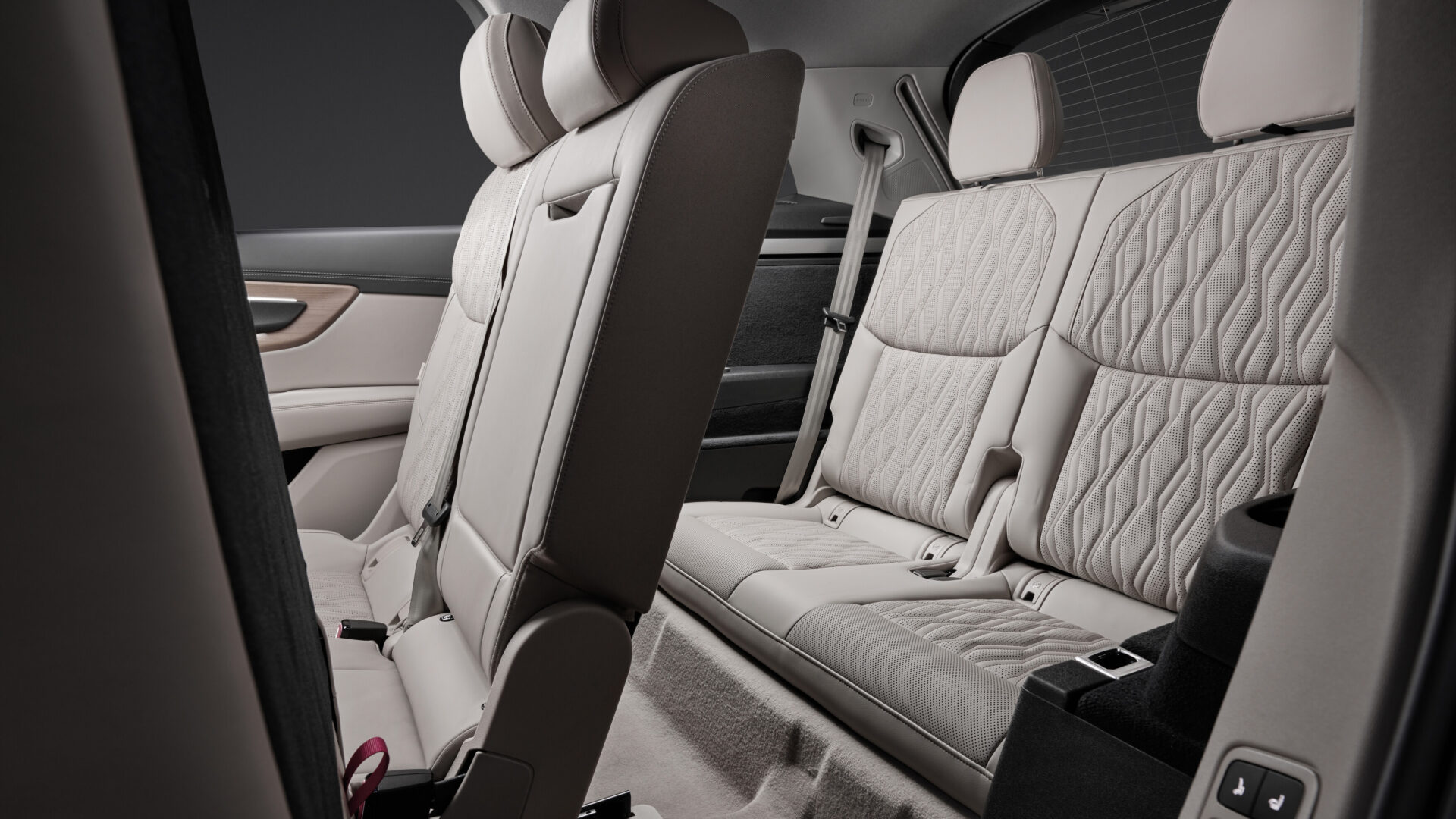 Interior view of a luxury car's back seat featuring plush, quilted upholstery and a center console.