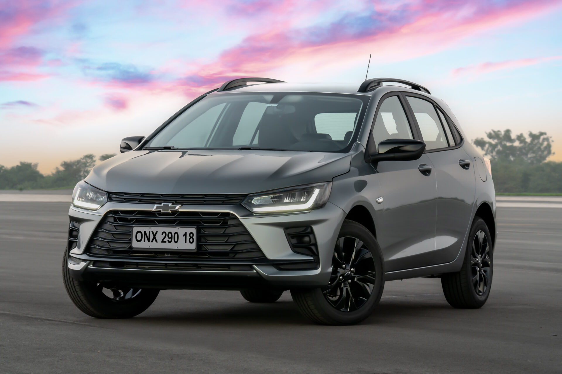 A sleek, gray Chevrolet SUV parked on a smooth surface with a colorful sky in the background.