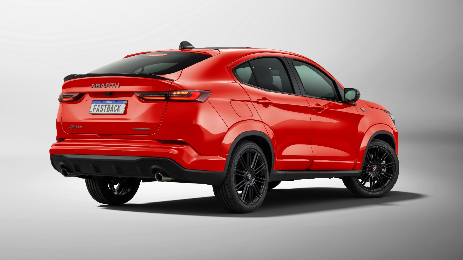 A rear view of a vibrant red Abarth fastback SUV, featuring sleek lines, a sporty design, and black alloy wheels.