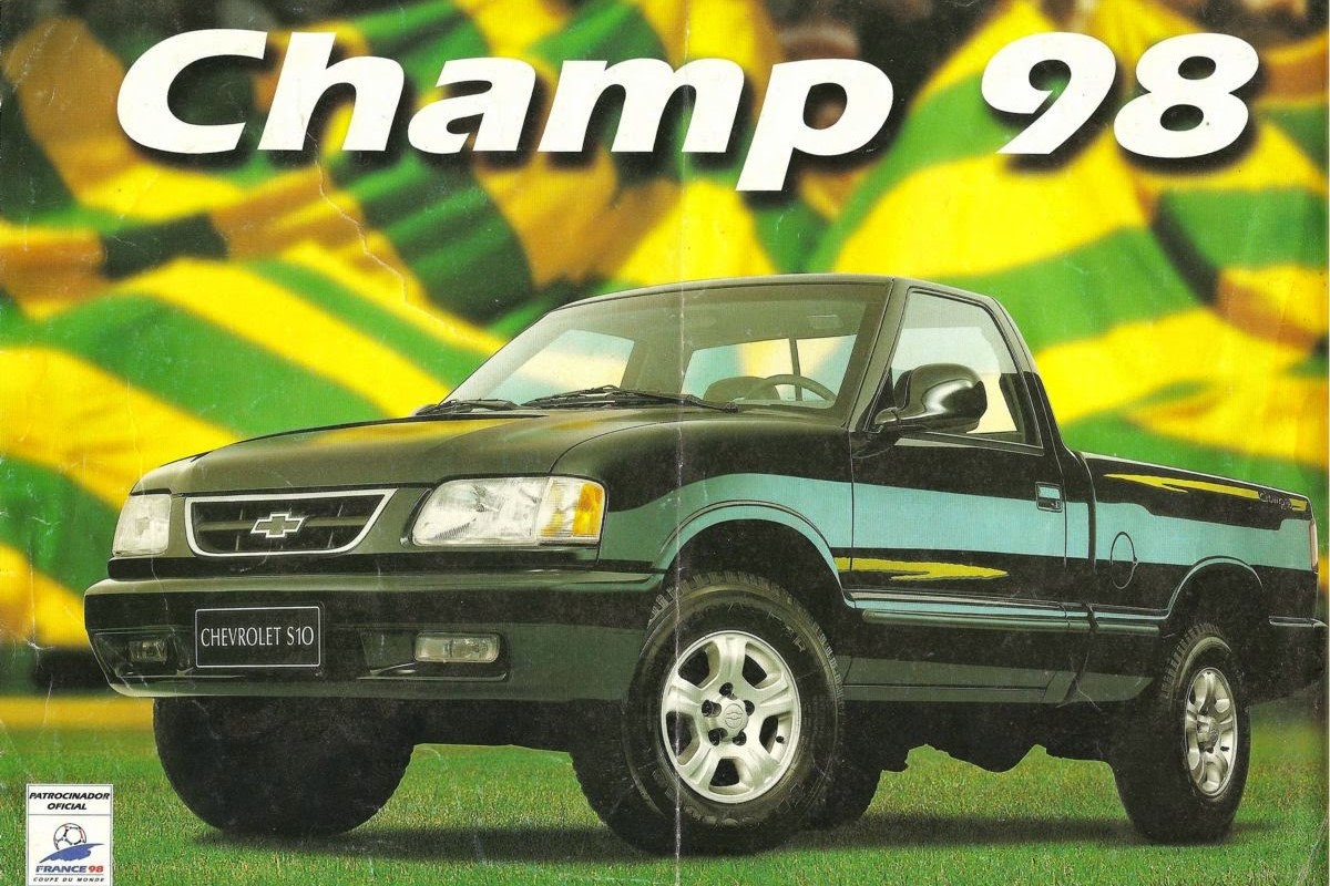 A Chevrolet S10 pickup truck showcased on a grassy surface with a colorful background featuring green and yellow stripes, labeled 'Champ 98'.