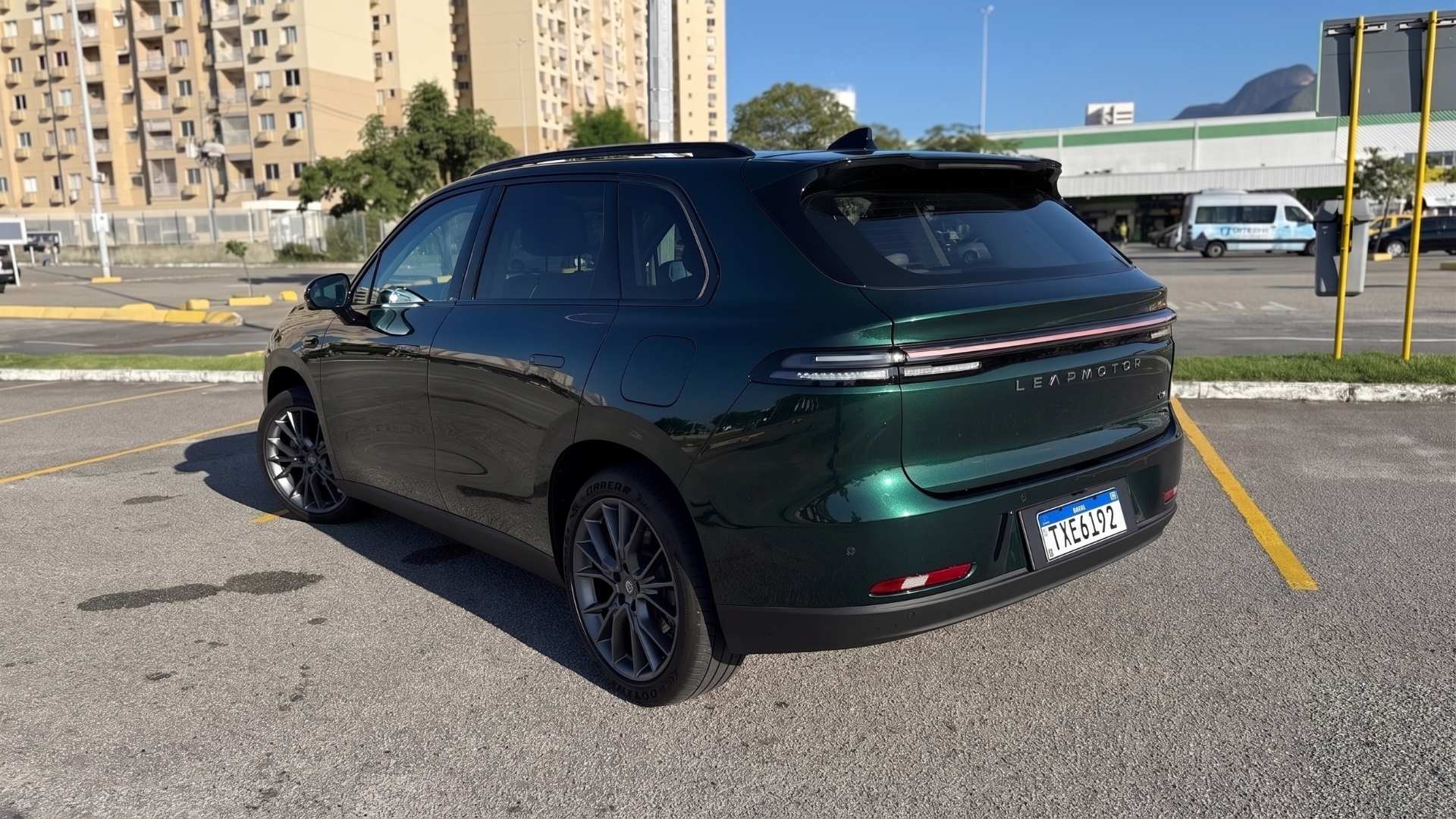 A green electric SUV parked in a lot, showing its rear and side profiles with modern design elements.