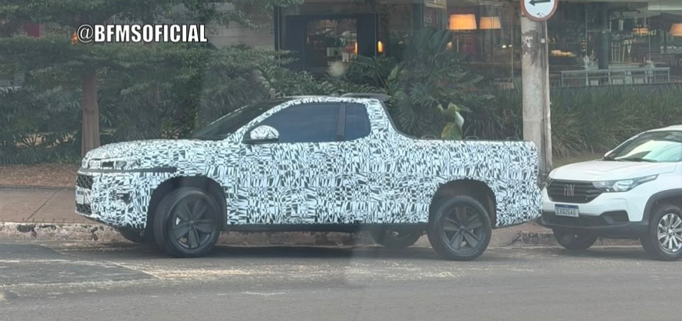 A camouflaged pickup truck parked on a city street, surrounded by lush greenery and other vehicles.