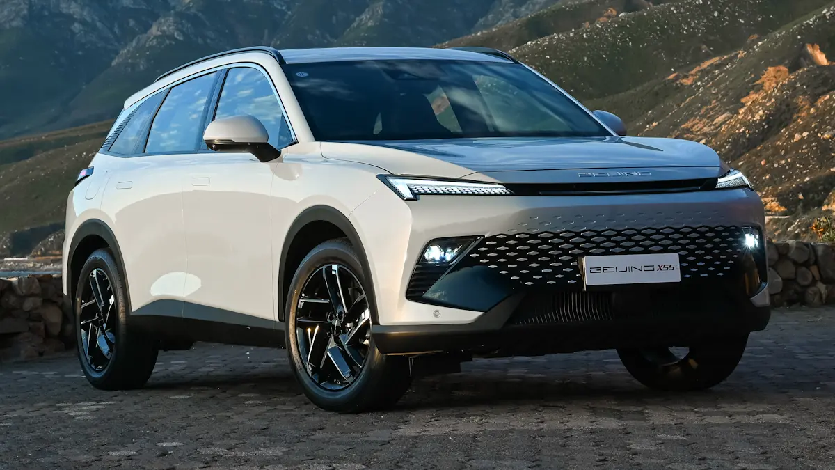 A sleek white SUV parked on a cobblestone surface with a mountainous background, showcasing its modern design and distinctive front grille.