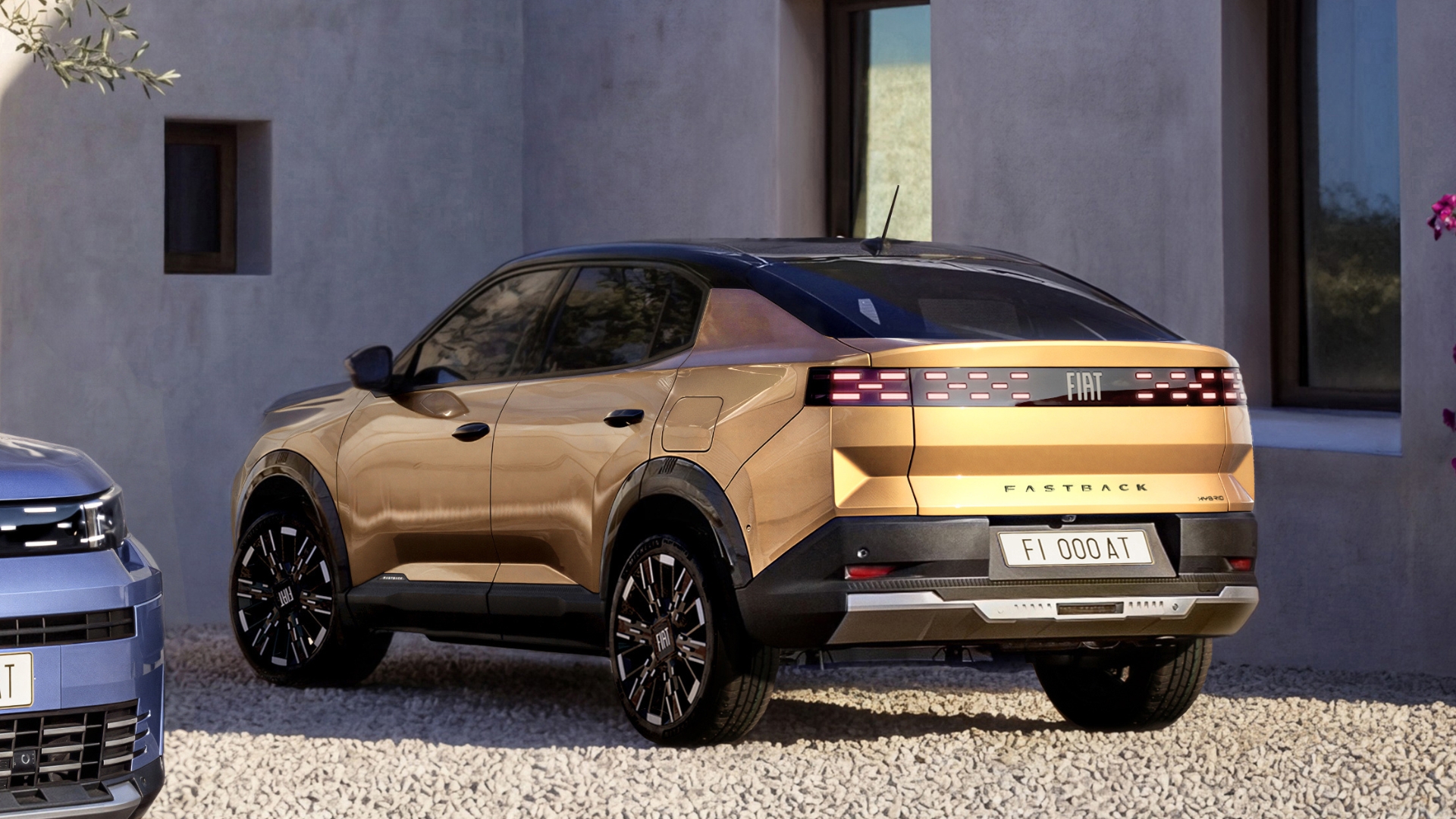 A side view of a gold Fiat Fastback parked in a gravel driveway, showcasing its sleek design and modern features.