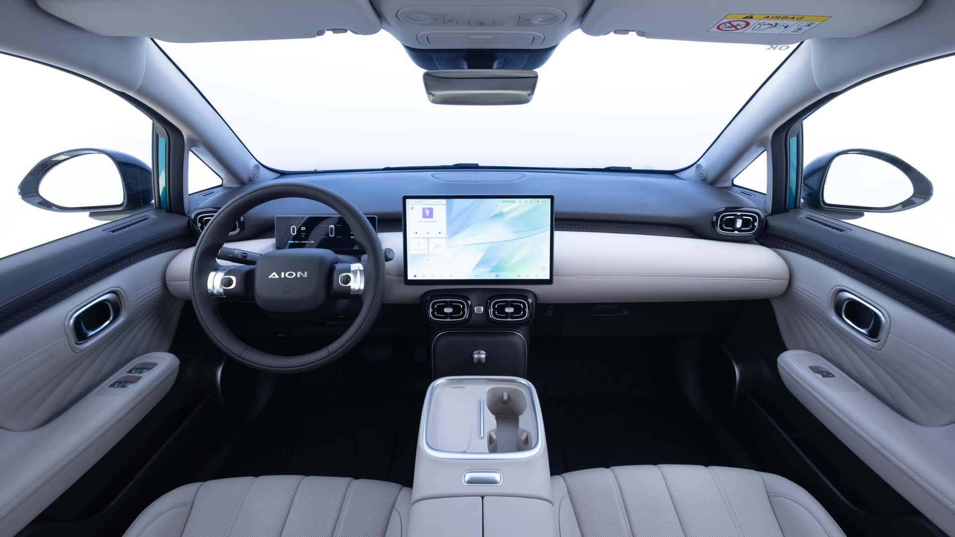 Interior view of a modern car featuring a steering wheel, a central touchscreen display, and sleek leather seats.