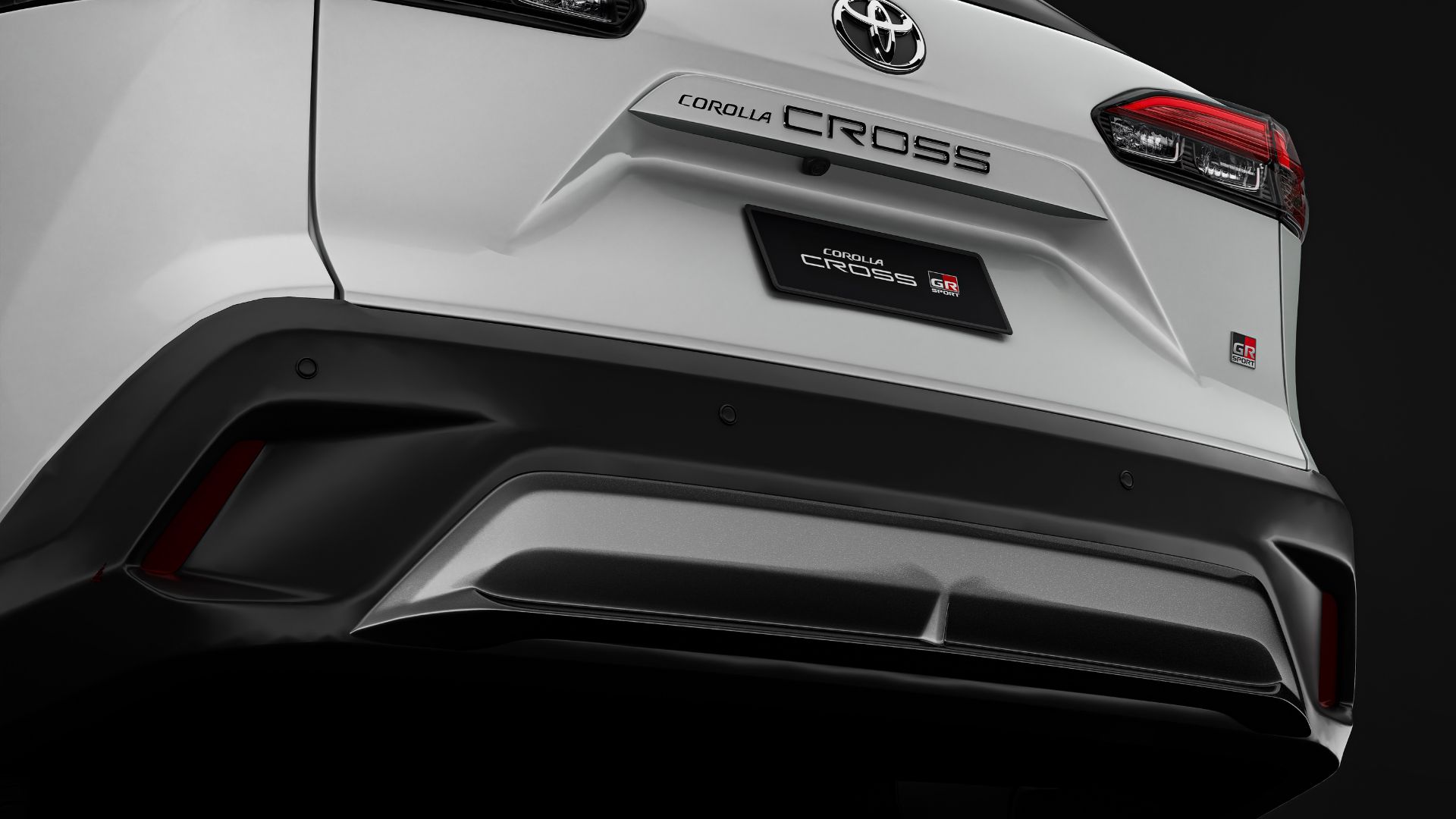 Close-up view of the rear bumper of a white Toyota Corolla Cross, showcasing the sporty design elements and GR Sport badge.