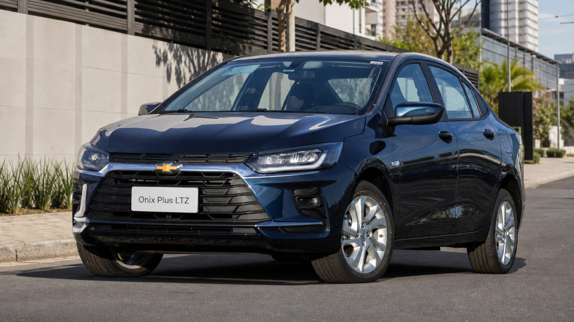 Front view of a Chevrolet Onix Plus LTZ parked on a city street, showcasing its sleek design and polished wheels.