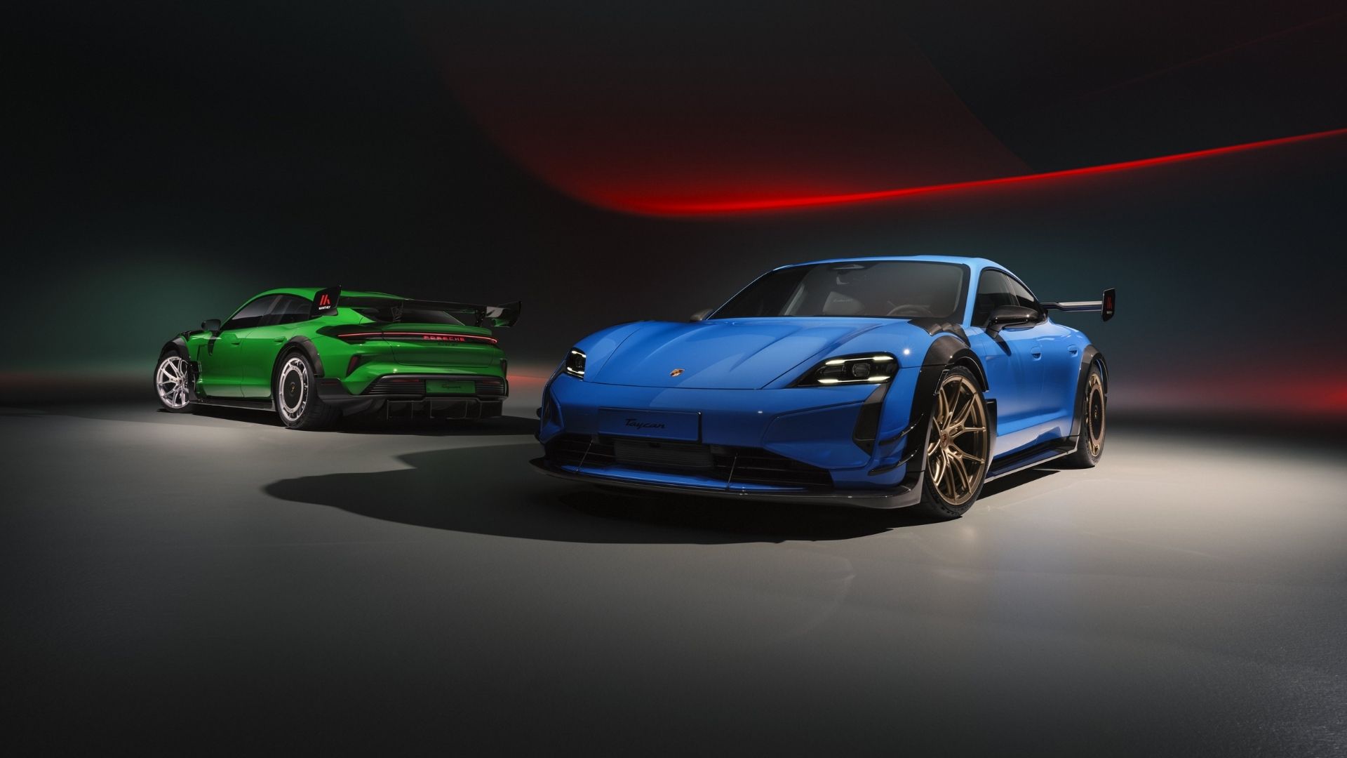 Two Porsche Taycan cars, one in blue and the other in green, displayed in a dramatic lighting setting.