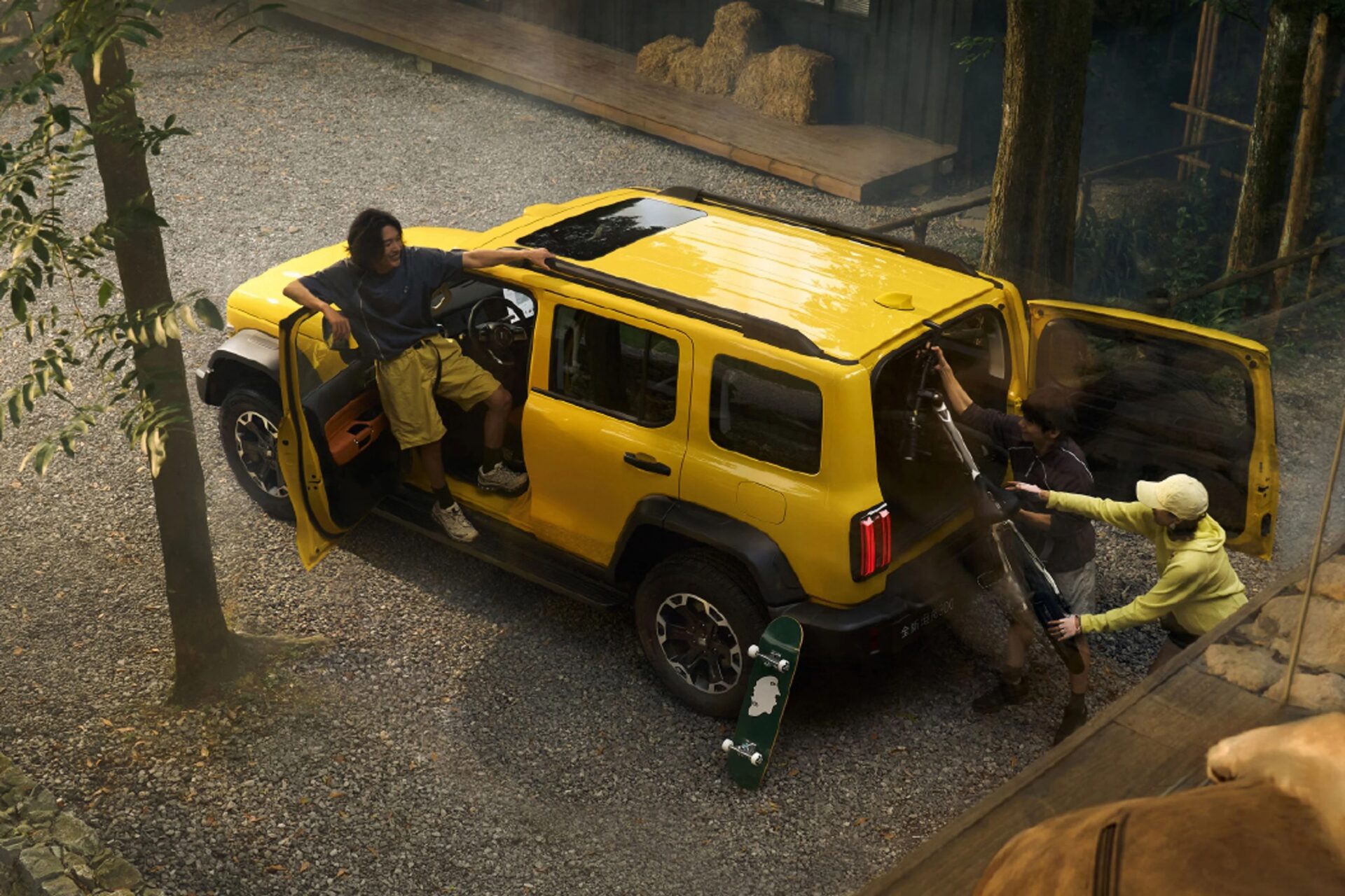 A group of young individuals loading equipment into a yellow SUV parked on gravel, with trees and a wooden structure in the background.