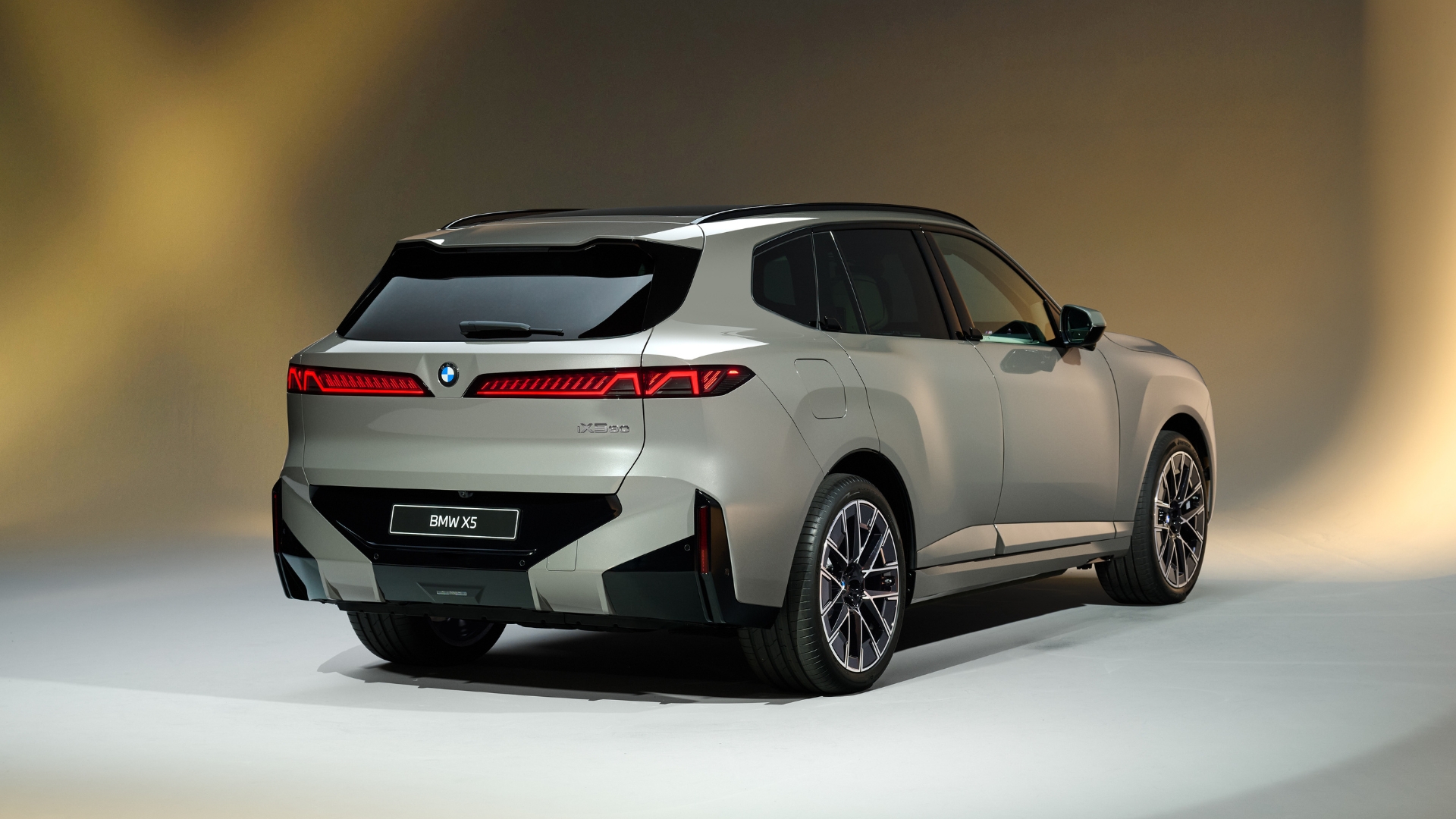 Rear view of a BMW X5 showcasing its modern design and sleek lines, set against a soft gradient background.