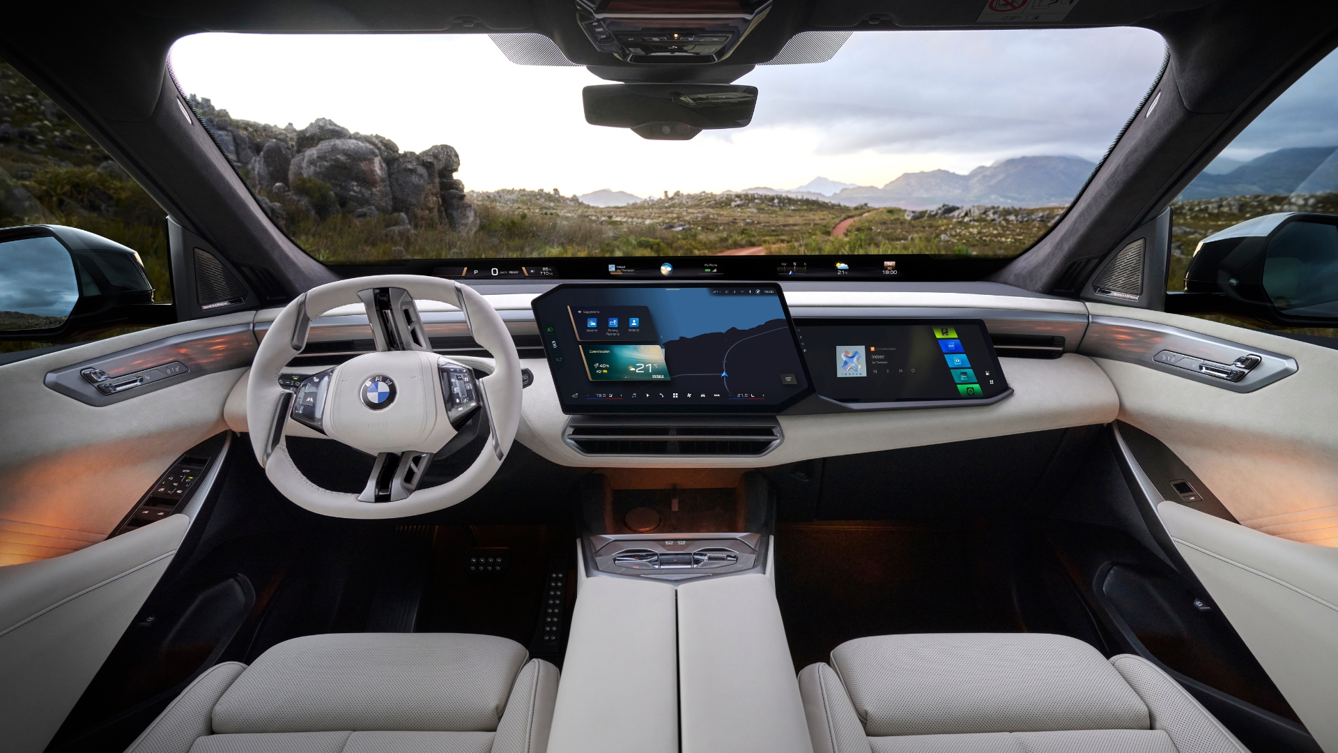 Interior of a modern BMW vehicle featuring a sleek dashboard with digital displays, a stylish steering wheel, and a panoramic view through the windshield showcasing a natural landscape.