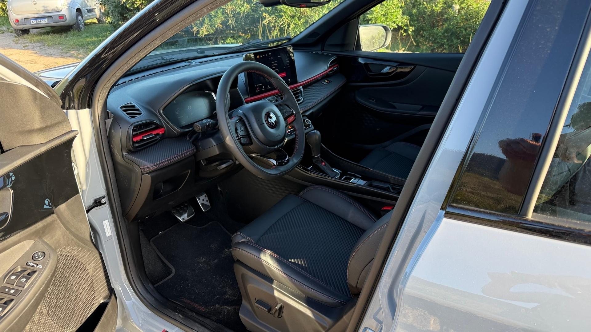 Interior view of a modern car, showing the driver's seat, steering wheel, dashboard with displays, and gear shift.