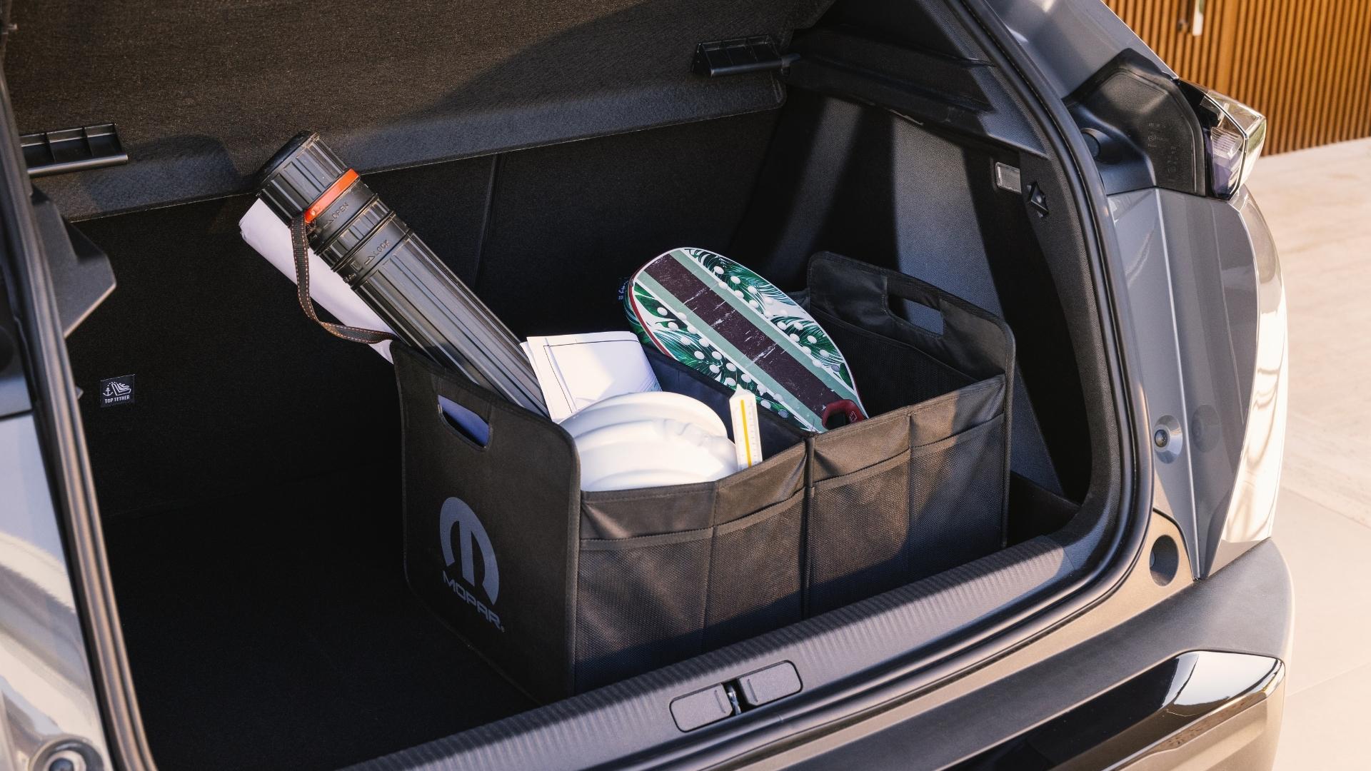 A view of the trunk of a car featuring storage bins containing sporting equipment and a rolled-up blueprint.