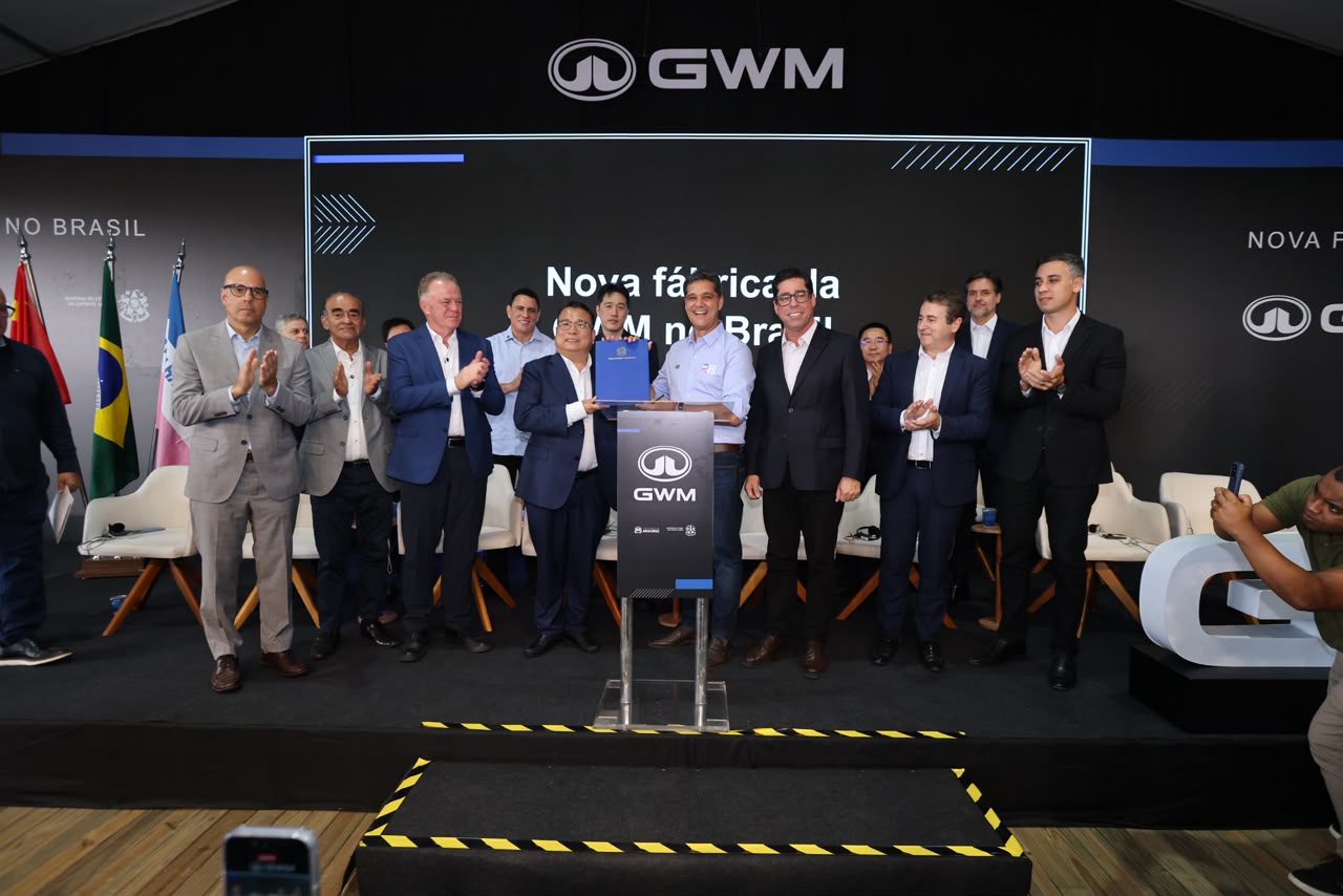Group of individuals at an event celebrating the opening of a new GWM factory in Brazil, with some holding a plaque and others clapping in support.