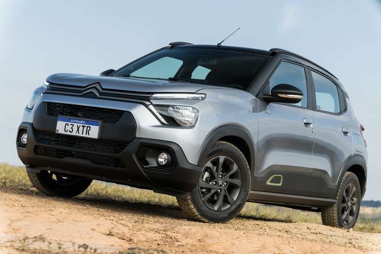 Um carro SUV compacto, modelo Citroën C3 XTR, na cor prata, posicionado em um terreno arenoso, com céu azul ao fundo.