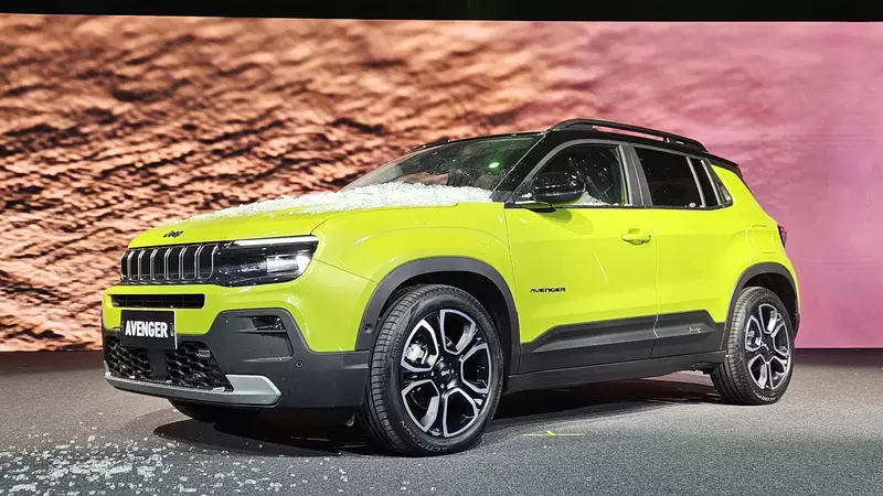 Um carro SUV da marca Jeep, modelo Avenger, na cor verde-limão, exibido em um evento com uma pista de fundo de terra.