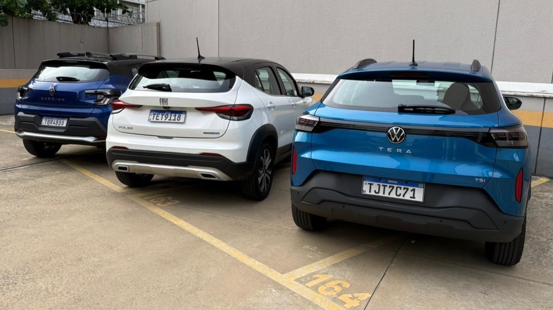 Três SUVs estacionados em um estacionamento, incluindo um Renault Kardian azul, um Fiat Pulse branco e um Volkswagen Tera azul.
