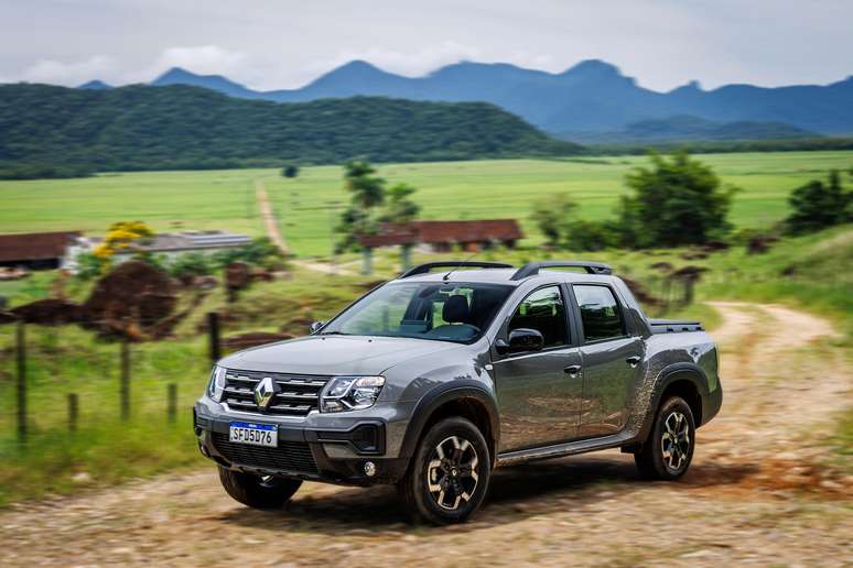 Uma picape Renault em estrada de terra com paisagem rural ao fundo e montanhas.