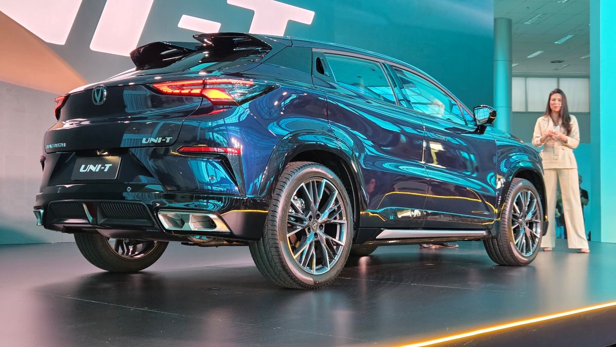 SUV UNI-T em um evento, visto de trás, com uma mulher apresentando ao fundo.