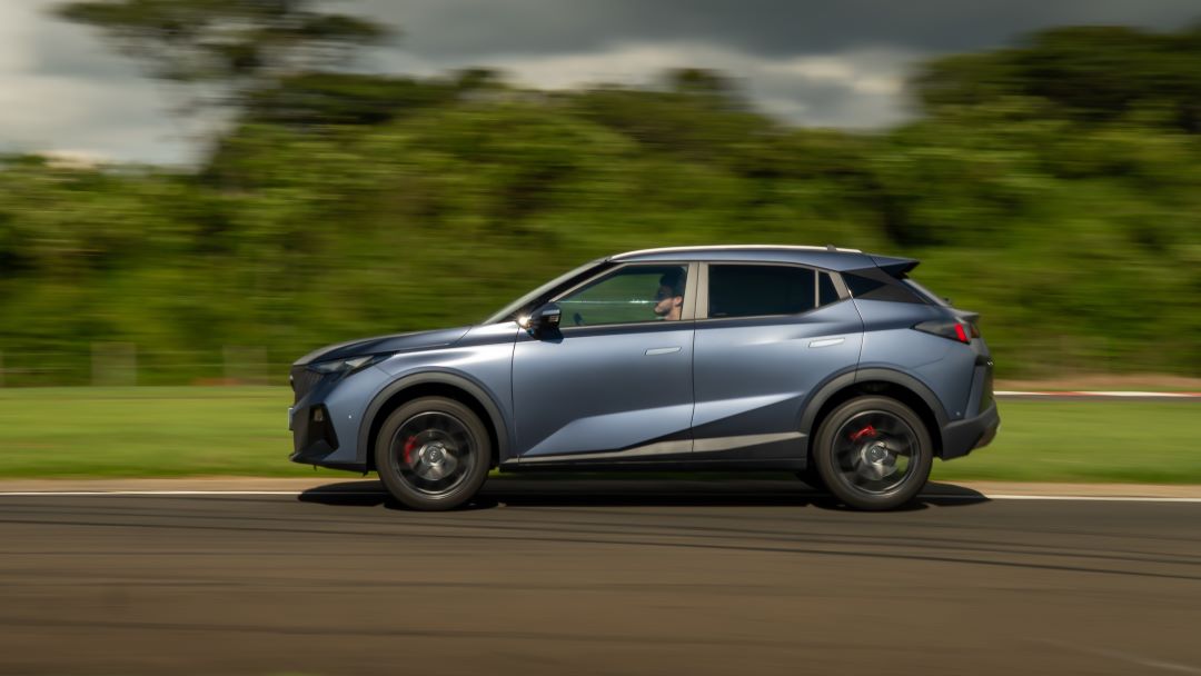 SUV azul em movimento em uma pista com vegetação ao fundo