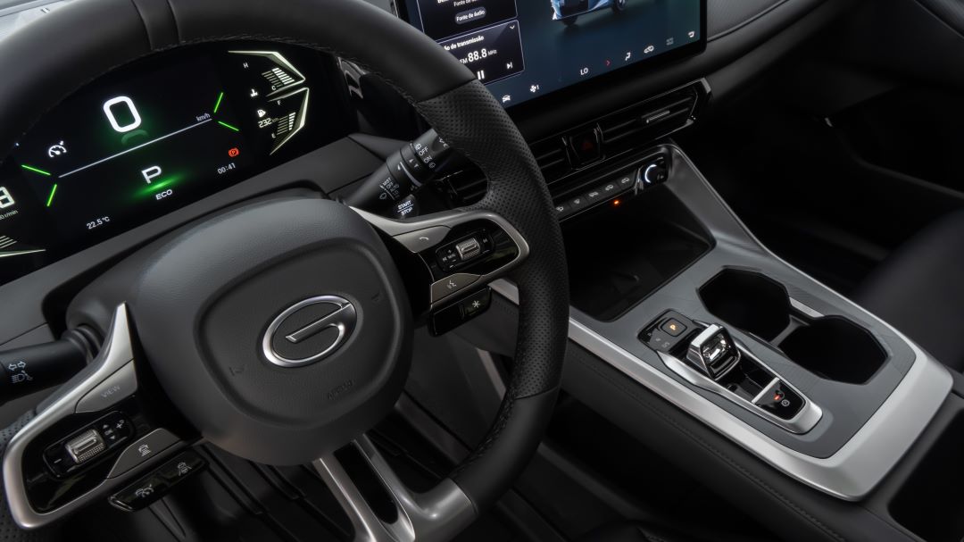 Painel de controle e direção de um carro moderno, destacando display digital, volante e console central.
