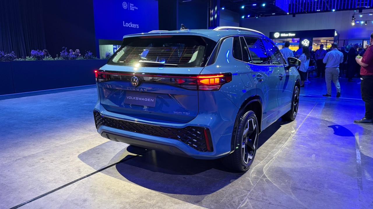 SUV Volkswagen Tiguan em exibição, visto de trás, com uma cor azul brilhante e iluminação ambiente moderna.