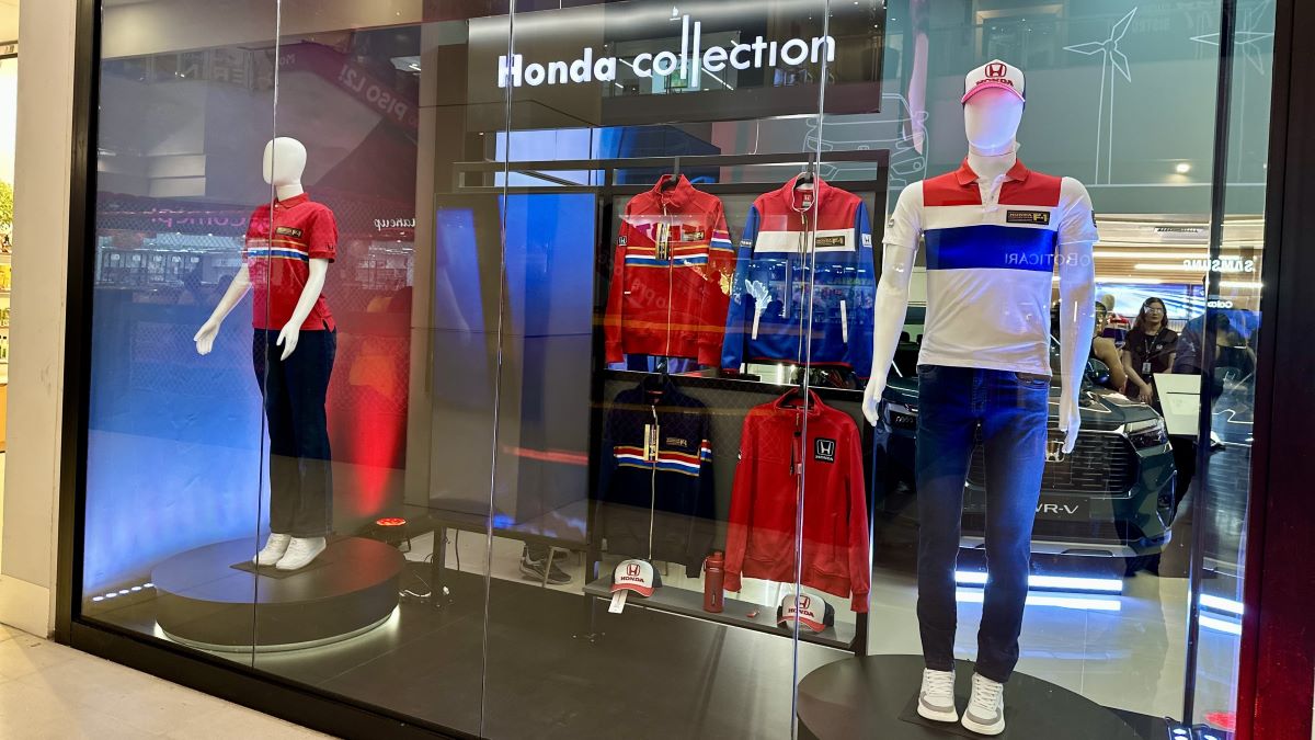Vitrine da coleção Honda com manequins exibindo roupas esportivas, incluindo camisetas e jaquetas, em um ambiente iluminado.