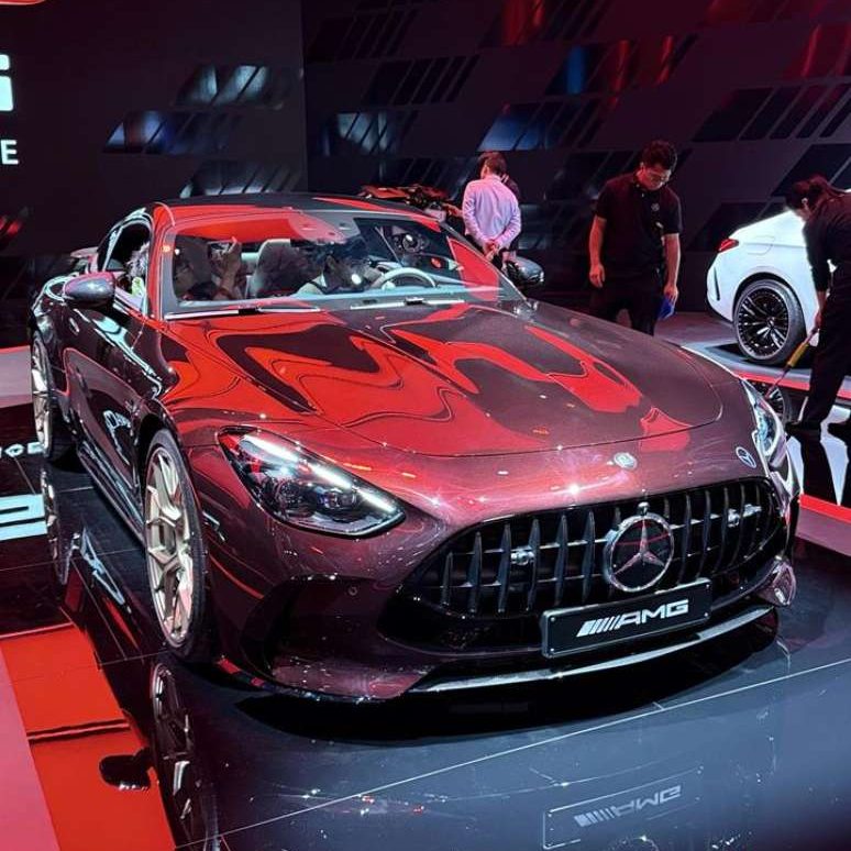 Carro esportivo Mercedes-AMG em um estande iluminado com luzes vermelhas, destacando seu design elegante e moderno.