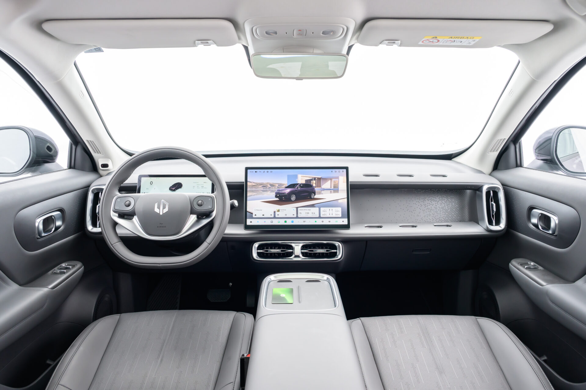 Interior moderno de um carro elétrico, com volante, painel digital e tela central grande.