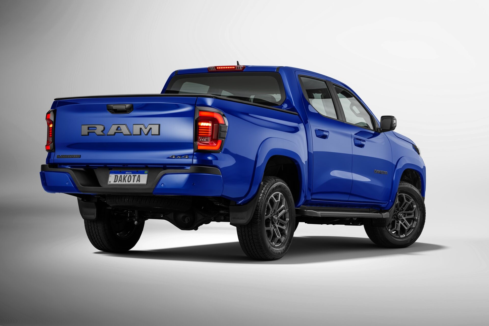 Rear view of a blue RAM truck with 'DAKOTA' license plate, showcasing the tailgate and 4x4 emblem.