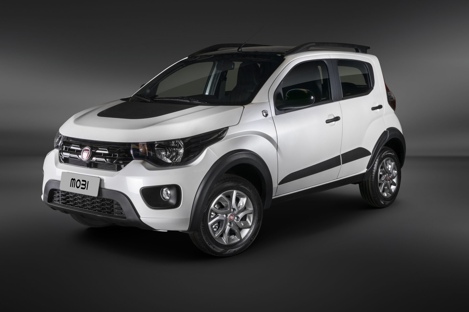Imagem de um carro branco Fiat Mobi, visto de ângulo frontal e lateral, com detalhes em preto e rodas prateadas. O carro está em um fundo escuro.