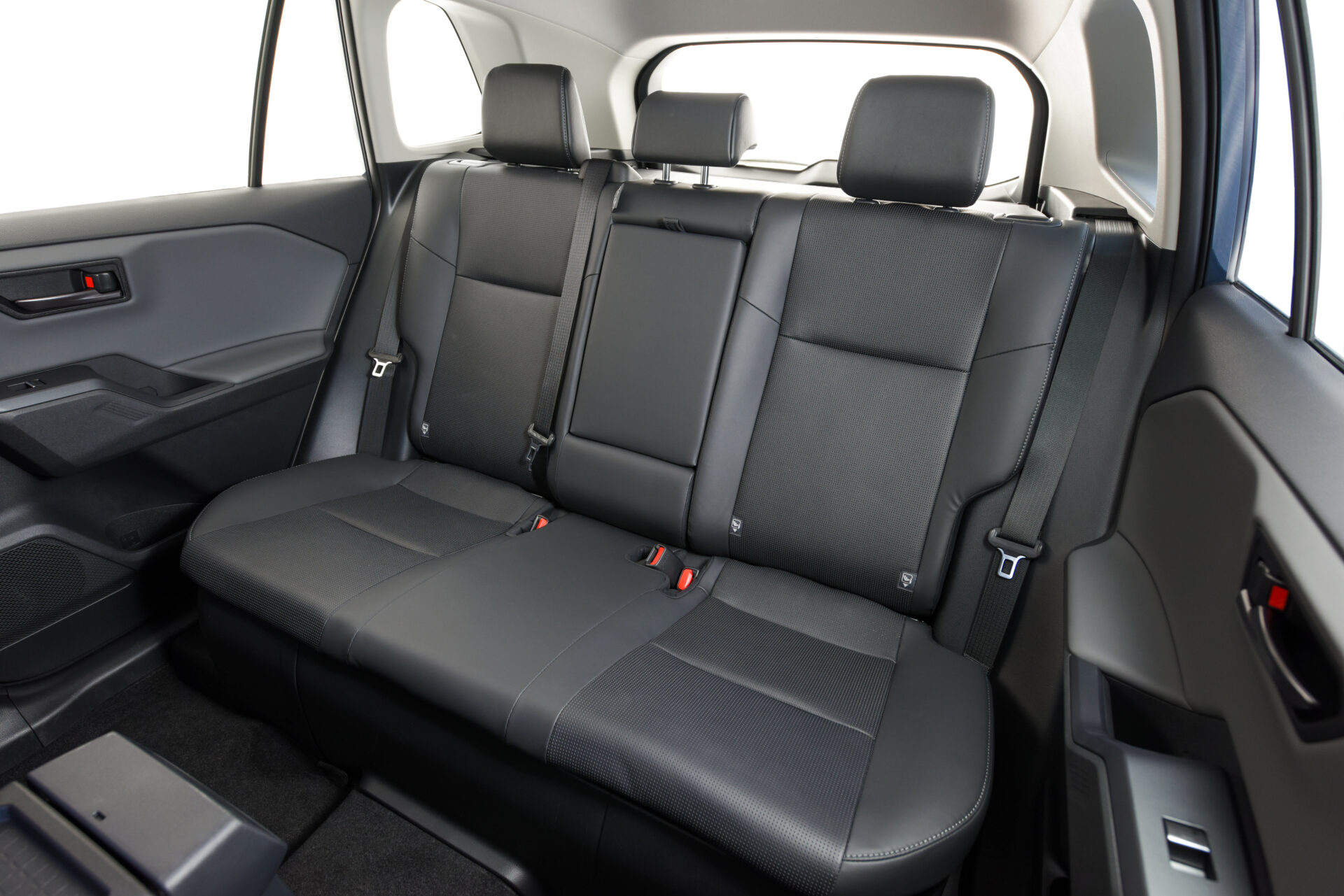 Interior de um carro mostrando os bancos traseiros em couro preto, com encostos de cabeça e cintos de segurança visíveis.