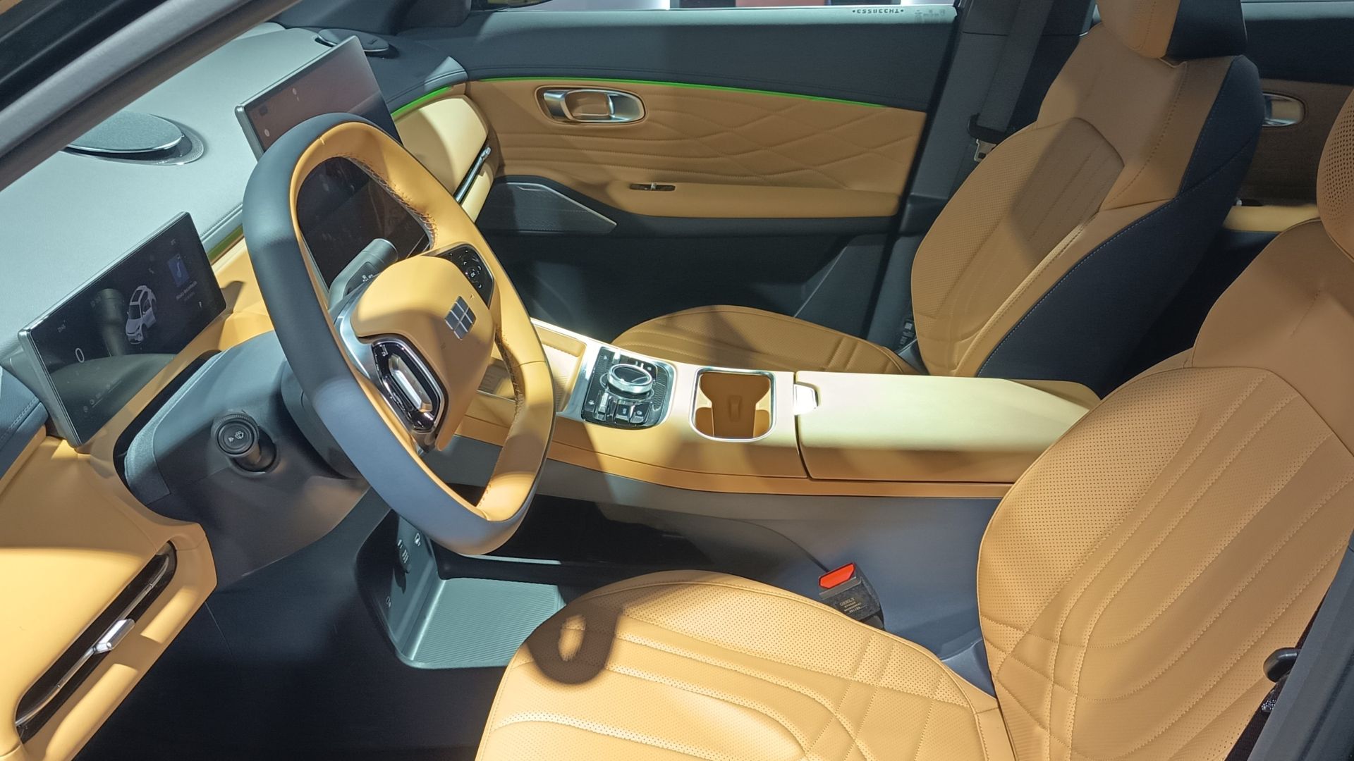 Interior de um carro moderno com bancos e volante em couro amarelo, telas digitais no painel e detalhes em verde.