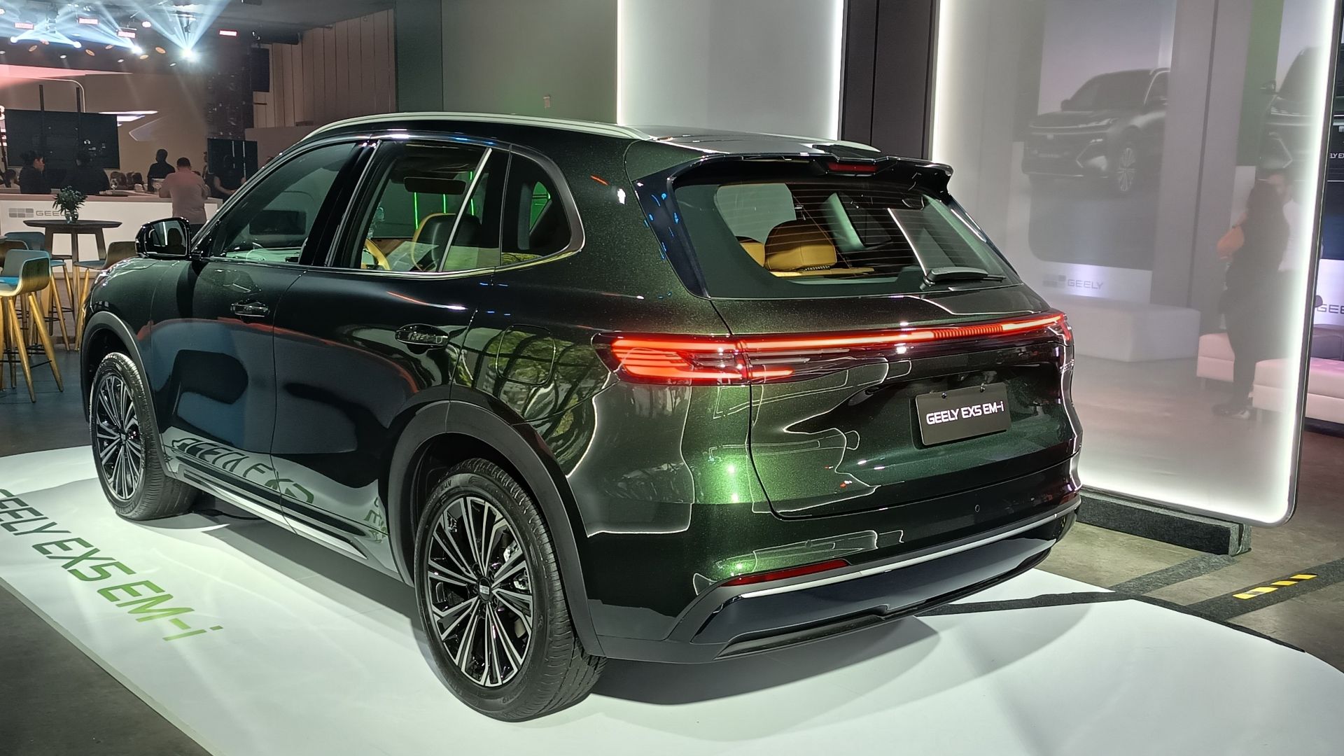SUV Geely ES5 EM-H em exibição, destacando a traseira em verde metálico sob iluminação de evento.
