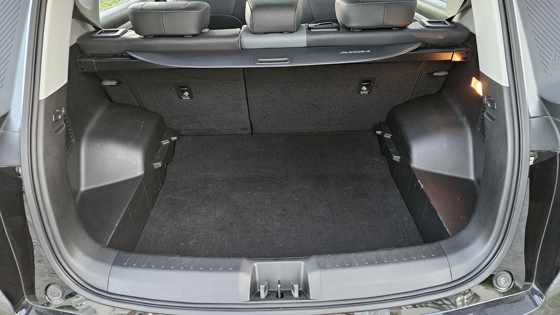 Interior de um porta-malas de carro, mostrando o espaço vazio e os acabamentos em preto.