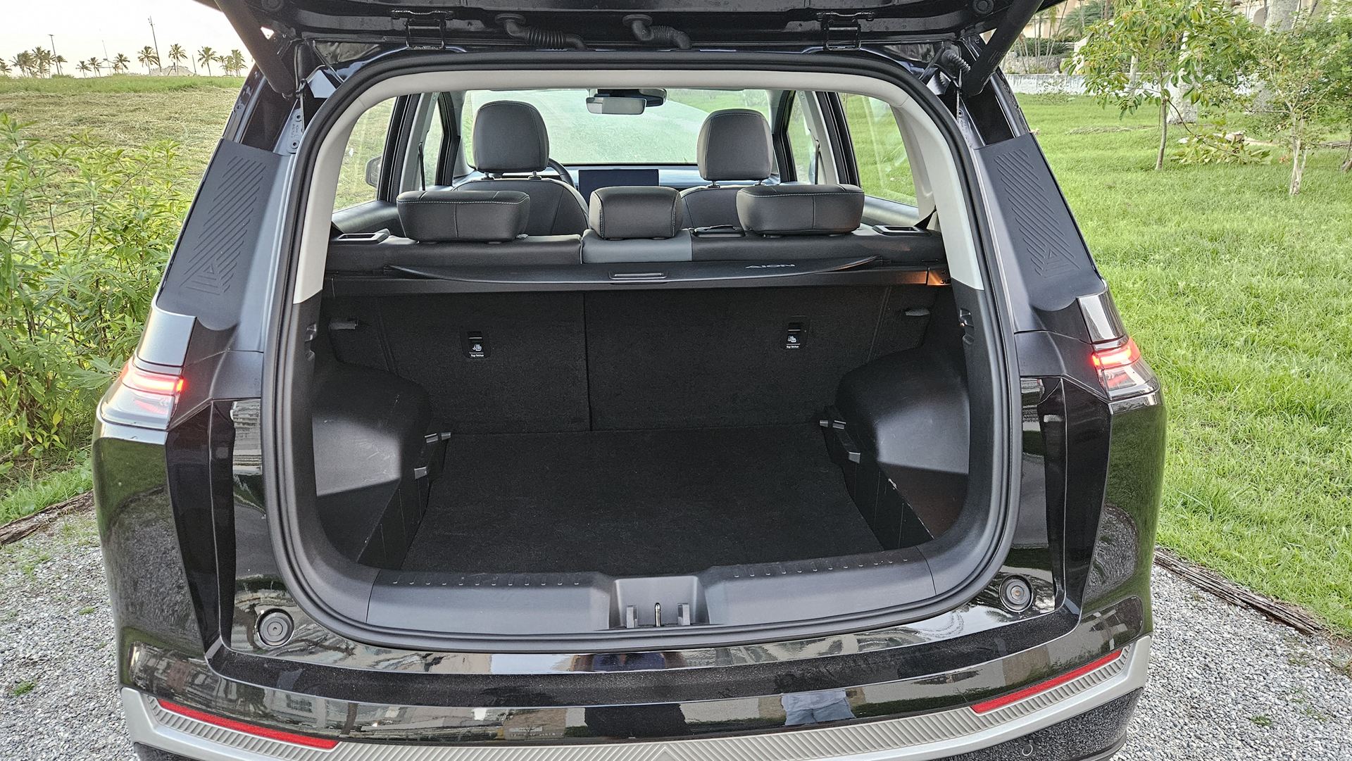 Traseira de um carro SUV com o porta-malas aberto, mostrando o interior espaçoso e os bancos traseiros.
